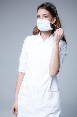 Genç bir doktor tek kullanımlık bir tıbbi maskeyi çıkarıyor. Maske eksikliği ve yüz koruması olmadan hastalanma riski