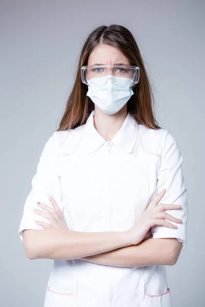 Amrican Student medic está em um casaco branco em uma máscara médica e óculos em um fundo branco durante uma pandemia — Fotografia de Stock