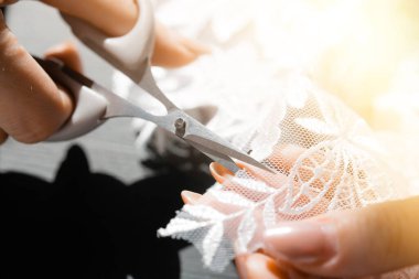 Yakın plan. Terzi, beyaz danteli terzi makasıyla keser.