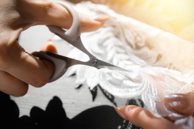 Yakın plan. Terzi, beyaz danteli terzi makasıyla keser.