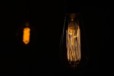 Yakın plan. Tungsten lifli Loft Edison lambası arka planda sıcak ışık yayar.