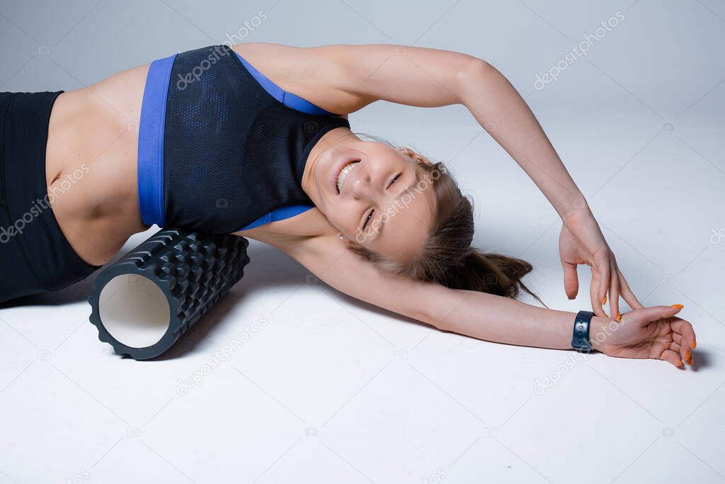 A yoga instructor massages the oblique and internal muscles of the abdomen with a sports roller of the fascia before training