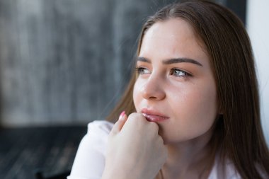 Ağlayan bir kızın, elini ağzında tutarak makyaj yaptığı yakın plan bir portresi. İş stresi ve hayattaki sorunlar.