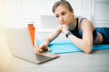 Pilates eğitmeni, dizüstü bilgisayardaki insanlara yönelik çevrimiçi bir dersin kaydı sırasında egzersizlere ara verdi. Evde spor yapıyorum.