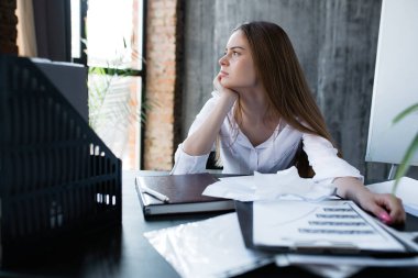 Bir kadın, bir iş günü boyunca dikkatlice pencereden dışarı bakar ve ekonomik kriz nedeniyle şirketinin ve işinin geleceğini düşünür..
