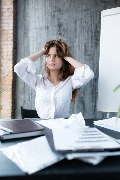 Портрет стрессовой девушки на работе, которая взъерошивает волосы и не знает, как все сделать в срок — стоковое фото