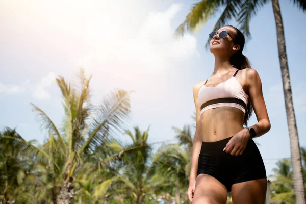 Krásná dívka ve slunečních brýlích stojí u letního slunce a palmy na dovolené na ostrovech. — Stock fotografie