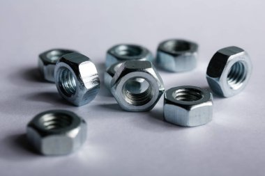 Metal fındıklar beyaz arka plana düzgünce serilmiş. Macro vuruldu. İnşaat ve onarım konsepti