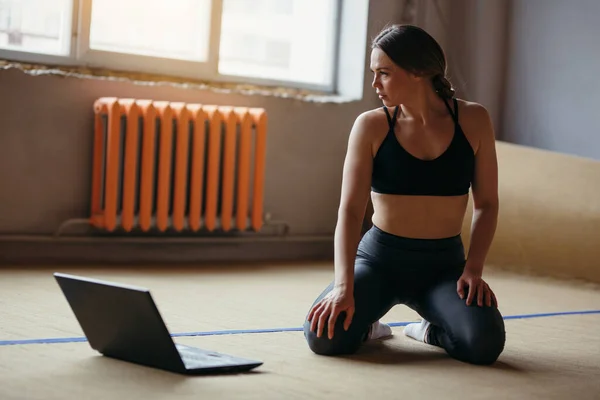 Fata practică yoga acasă în fața laptopului. Sportivul se uită la cum să efectueze exerciții în timpul clasei de comunicare video . — Fotografie, imagine de stoc