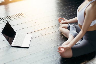 Görüntüyü eklemek için siyah ekranlı dizüstü bilgisayarın yakın plan görüntüsü ve video altında Lotus pozisyonunda meditasyon yapan bir yoga eğitmeni.