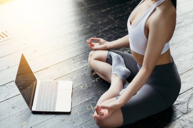 İnternette notubuk 'un önünde meditasyon yapan Lotus pozisyonunda bir kız figürü. Güneş Stüdyosu