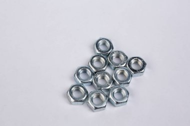 Beyaz arka planda bir sürü krom fındık var. Onarım parçalarının kapatılması