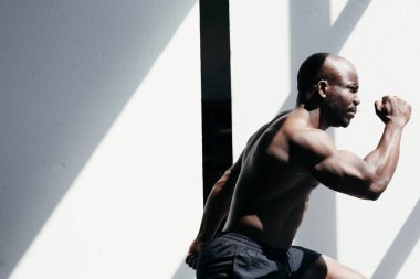 Beyaz arka planda koşan kaslı Afrikalı Amerikalı adam