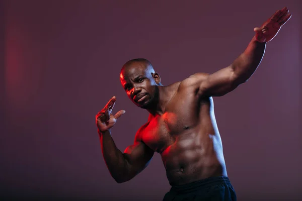El deportista africano con el torso en relieve hace un movimiento de danza Dab. El cuerpo está resaltado en neón rojo . — Foto de Stock