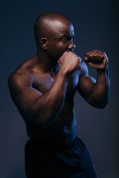 Publicidad disparó Boxer afroamericano de perfil con una caja de torso desnuda sobre un fondo de neón azul . — Foto de Stock