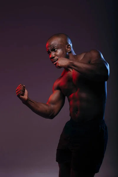 Portrét pohledného svalnatého afrického amerického boxera s neonově červeným světlem nahoře bez ve studiu — Stock fotografie