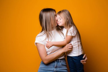 Anne ve kızının portresi. Sarı arka planda şefkatli kucaklaşmalar. Aile kavramı