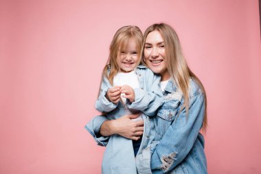 Güzel anne küçük kızına sıkıca sarılır. Pembe arka planda sağlıklı ebeveyn-çocuk ilişkisi kavramı