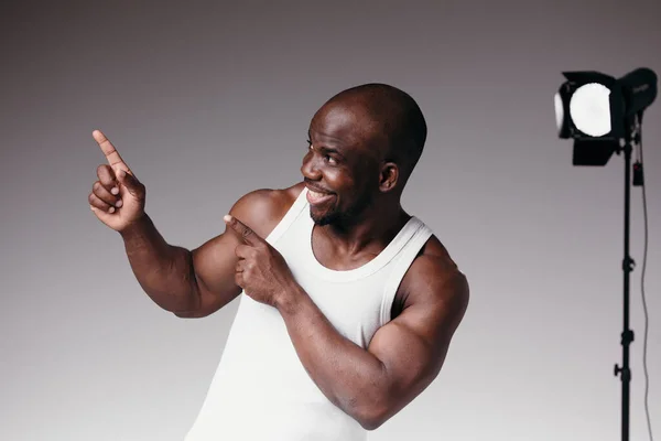 Modelo masculino de pele escura com músculos em relevo posando na câmera em um estúdio de fotos — Fotografia de Stock