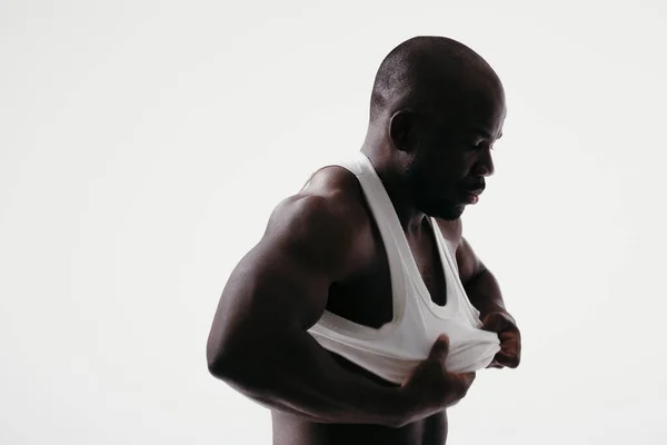 Retrato de un hombre musculoso de piel oscura. Atleta se pone una camiseta blanca — Foto de Stock