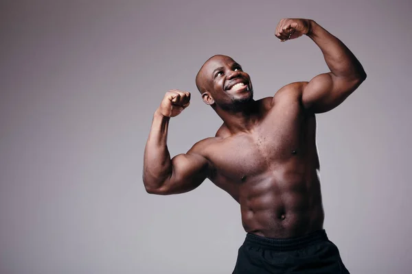 Retrato de bonito muscular afro-americano homem mostrando nu tronco e bíceps braços sorrindo para a câmera no estúdio — Fotografia de Stock