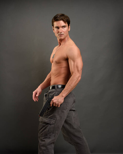 Сексуальный мужчина держит пистолет
