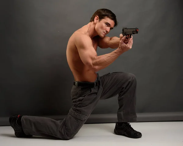 Der sexy Mann hält eine Pistole — Stockfoto