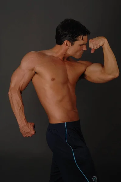 The handsome fitness man shows his muscles — Stock Photo, Image