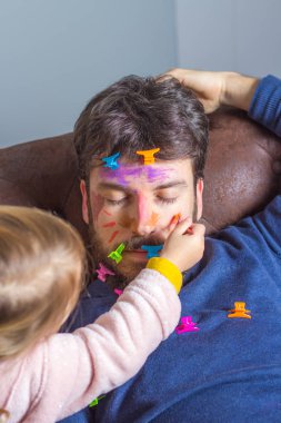 Küçük kızının haylazlığına maruz kalan genç bir baba. Küçük kız, babasının kanepede uyurken yüzünü fırça ve suluboya boyayla boyuyor.