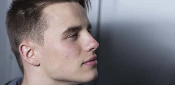 Yan görünüş, kendinden emin bir gencin bakışlarını başka yöne çeviren portresi. Arkaplan kopyalama alanı.