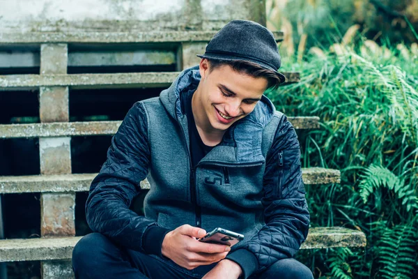 Gelukkige Jongeman Met Een Stijlvolle Hoed Die Buiten Zit Glimlacht — Stockfoto