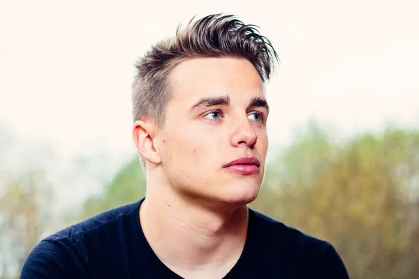 Arka planda ağaçlık alan olan genç erkek modelin yakın plan portresi..