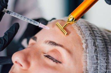 Genç bir kadının alnına botoks yapılan şırınganın yakın görüntüsü. Estetik tıp konsepti.