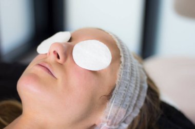 Güzellik salonunda gözleri koruyucu, rahat ve yüz bakımına hazır genç bir kadının yakın çekimi..