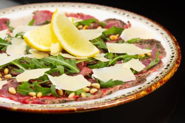 Peynirli biftek carpaccio ve bir dilim limon.