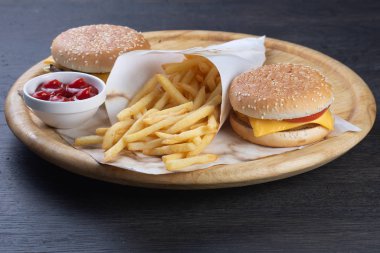 Tahtadaki hamburgerler. Biftek, peynir ve sebzeli çizburger. Tavuk nugget, peynir, domates, salatalık ve soğanlı hamburger. Ketçaplı patates kızartması.