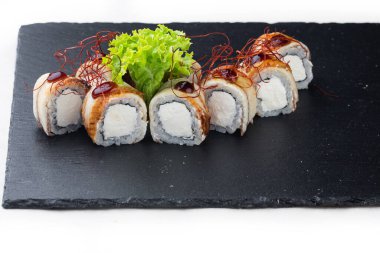Ton balıklı maki suşi, yumuşak peynir ve taş tahtada balzamik sos. beyaz arkaplanda