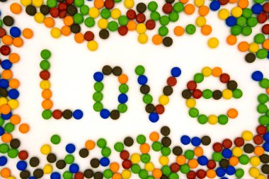 Aşk kelimesi yuvarlak şekerlerin arka planında yer alır.