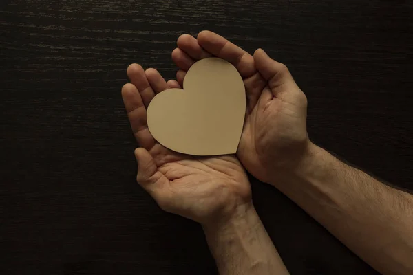 Mãos Estendidas Contra Uma Mesa Madeira Coração Cortado Papel Branco — Fotografia de Stock