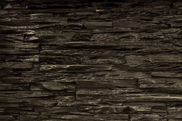 Texture of black stone laid on the wall