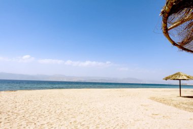 Tropik plaj - Ürdün 'deki Japon Bahçeleri. Güneşli bir gün. Kızıl denizin kıyısında beyaz kum.