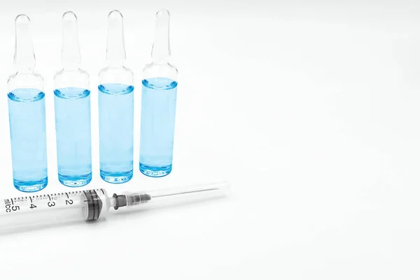 ワクチンの注射器と4つのガラスのバイアルは ラベルの白い背景とスペースに青色で表示されます この薬は コロナウイルス感染の予防 予防および治療に使用されます — ストック写真