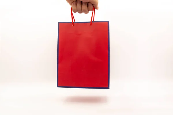 ブルーのストライプと滑らかな赤のデザイナー段ボール製のギフトバッグは 手の中に影 サイドビュー — ストック写真