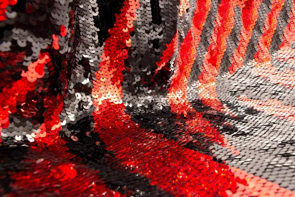 The texture of red and black sequins arranged in stripes on a graceful, elegant, evening dress. The concept of a glamorous background.