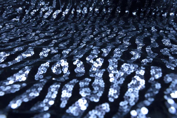 Texture of black and dark blue round sequins on a modern, elegant, evening dress. The concept of the club style in 2020.
