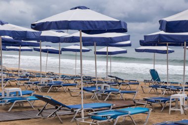 Kumsal, güverte sandalyeleri ve fırtınalı havada kumsal şemsiyeleri.
