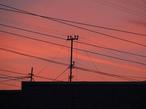 Television antennas and wires in the background of sunset on a blue sky with traces of an airplane — Stock Photo, Image