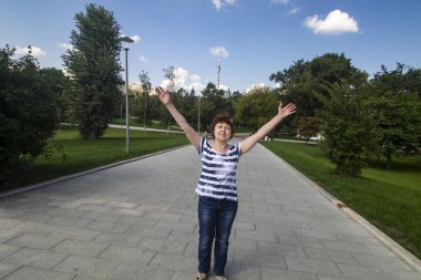 Parktaki arka bahçede elleri havada bir kadın var.