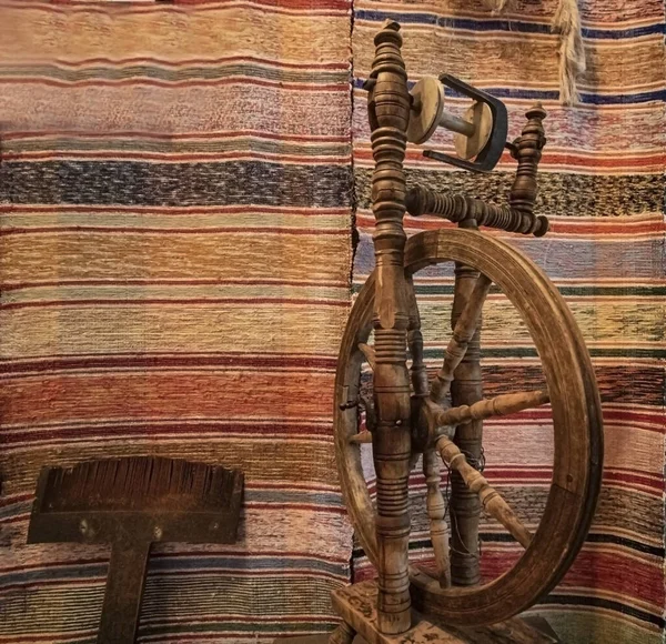 Rus gerçekliğinin ulusal antik araçları, halıların arka planında yün ipliği yapmak için dönüyor