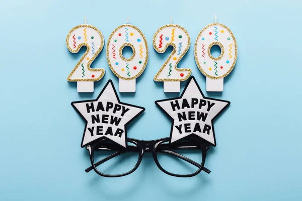 2020 świece i okulary noworoczne na niebieskim tle. Szczęśliwego Nowego Roku — Zdjęcie stockowe